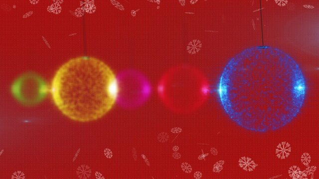 Animation of falling snow over christmas baubles on red background