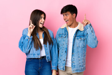 Young couple over isolated pink background intending to realizes the solution while lifting a...