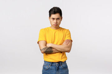 I am mad at you. Angry and displeased, offended defensive asian man in yellow t-shirt, cross arms...