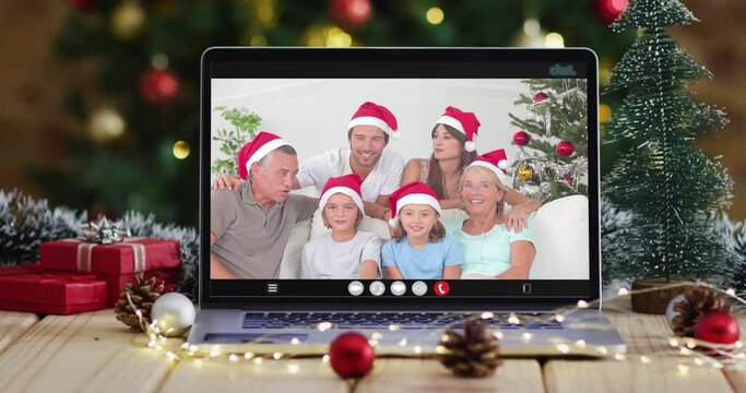 Happy family wearing snata hats on video call on laptop, with christmas decorations and tree