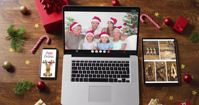Happy family wearing santa hats on laptop video call, with christmas decorations and tree