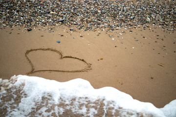 The heart symbol on the beach is drawn on the yellow sands of the shore. Valentine's Day.