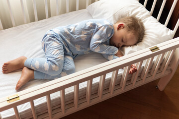 top view Cute little 2-3 years preschool baby boy kid sleeping sweetly in white crib during lunch...