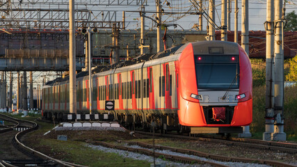 Modern russian intercity high speed train under the bridge at sunset. Industrial landscape with passenger train on railroad in Europe. Commercial suburban transportation concept