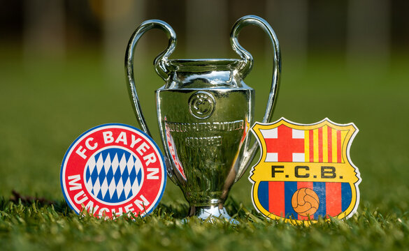 August 27, 2021 Bavaria, Munich. The Emblems Of Football Clubs FC Barcelona And FC Bayern Munich And The UEFA Champions League Cup On The Green Lawn Of The Stadium.