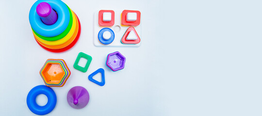 Children's educational toys: a pyramid and sorters lie on a white background with a place for text. top view, flat lay, copy space, isolate