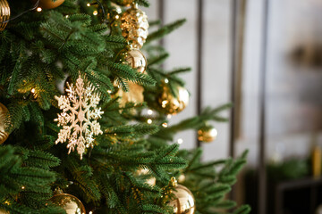 a fragment of a decorated Christmas tree with golden toys, taken close-up in a living room. The concept of a holiday and home comfort.
