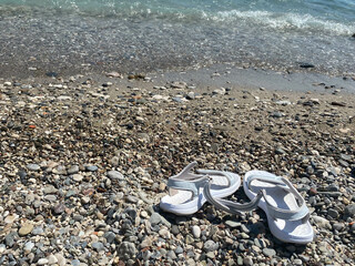 flip flops on the pabble beach. Summertime sea holiday concept. Top view. Copy space