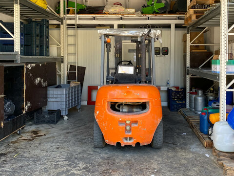 An Orange Industrial Forklift Truck Stands In A Garage For Maintenance