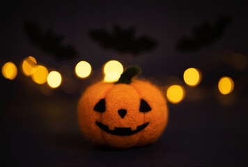 Halloween pumpkin. Jack o lantern head on dark background with bokeh. Wool felted pumpkin.