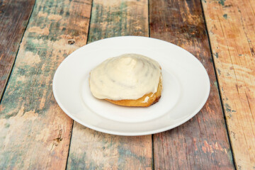 Cinnamon roll bun with sweet topping on wooden table