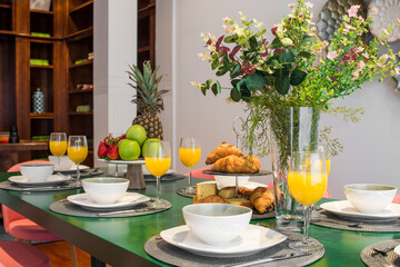 Dining table with breakfast service, juices, fruits and pastries ready to eat in a vacation rental apartment