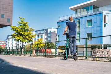 Young man riding an electric scooter down the streets in Malmo. Ecological transportation concept. Sideways man riding an e-scooter © Aerial Film Studio