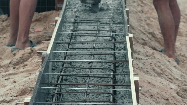 Pouring with liquid concrete of formwork with reinforced iron. Construction of building foundation.