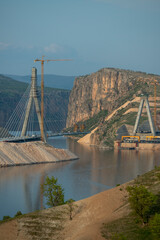 Obraz premium General view of the construction process of a suspension bridge to cross a lake between mountains