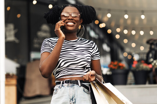 african woman, with colorful shopping bags, talking on mobile phone during christmas shopping at mall