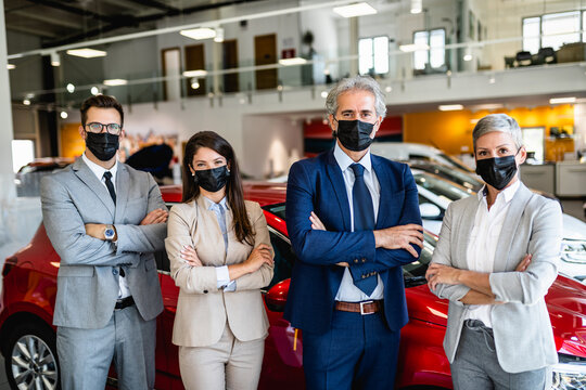 Salespeople With Protective Face Masks Working At Car Showroom. Covid 19, Coronavirus Concept.