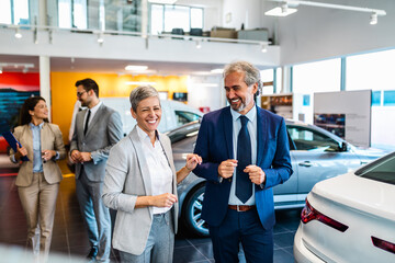 Team of happy salespeople are working together at car dealership.