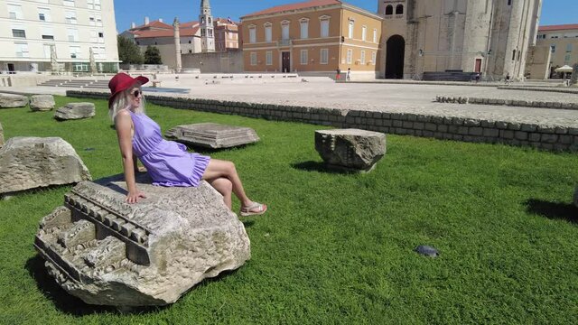 Woman with hat in the Ancient Roman Forum of Zadar city of Croatia on Adriatic Sea and capital of Dalmatia. Roman square with Church of St Donatus and Cathedral of St. Anastasia with the bell tower.
