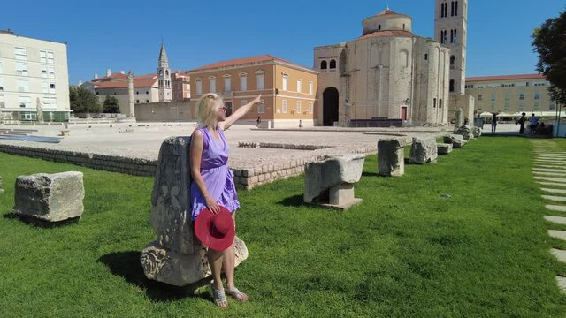 Woman with hat in the Ancient Roman Forum of Zadar city of Croatia on Adriatic Sea and capital of Dalmatia. Roman square with Church of St Donatus and Cathedral of St. Anastasia with the bell tower.