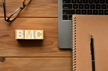 On the table there is a word cube lined BMC with laptop computers and glasses. It is an...
