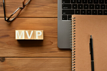 On the table there is a word cube lined MVP with laptop computers and glasses. It is an...