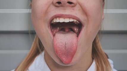 The young girl opens her mouth and shows her tongue. Stamatology theme.