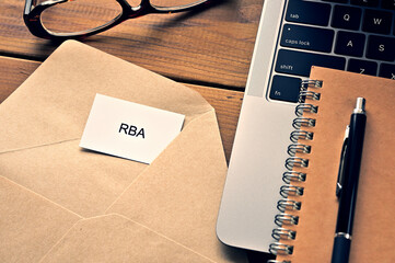 On the table, there is a card with the word of RBA which is an abbreviation for Responsible Business Alliance along with a laptop computer and glasses.
