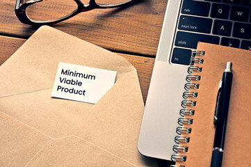 There is a laptop, a pen, an envelope, and a card with Minimum Viable Product written on it.