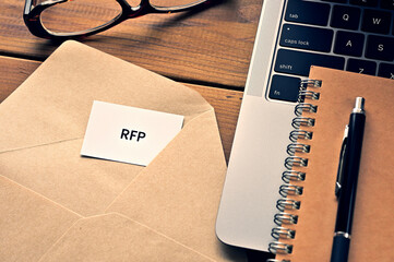 There is a laptop, a pen, an envelope, and a card with RFP which is an abbreviation for Request For...