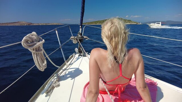 Woman sunbathing on bow of a sailboat, navigating to Telascica and Kornati national parks of Croatia. Adriatic Sea of Europe.