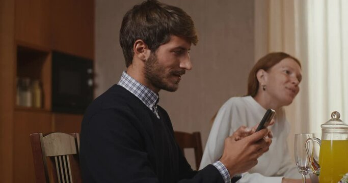 A young man starts a video call on his mobile the whole family joins him
