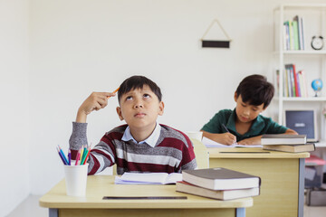 Fototapeta na wymiar Asian student boy thinking during exam in a classroom