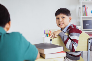 Smiling Asian student sitting on the chair while looking to the camera in a classroom