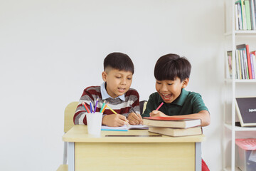 Two happy Asian students studying and writing together in the classroom