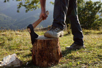 Man with axe cutting firewood outdoors, closeup