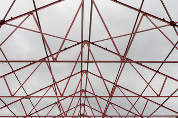 Red steel structure skeleton with cloudy sky in the background