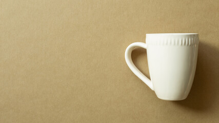 White mug cup isolated on brown background. top view, copy space