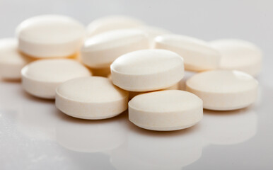 Fototapeta na wymiar Closeup view of heap of identical round pills on white surface..