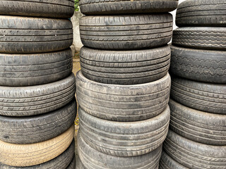 Used worn out Automobile tyres stacked one on top of each other
