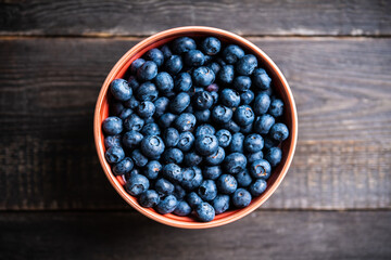 Blueberries in ceramic bowl on rustic wooden background. Selective focus. Shallow depth of field.