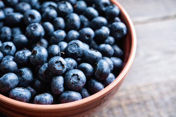 Blueberries in ceramic bowl on rustic wooden background. Selective focus. Shallow depth of field.