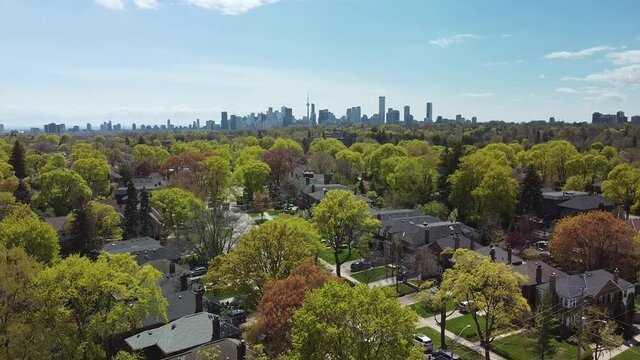 A shot descending into a residential neighbourhood with Toronto's skyline in the distance.