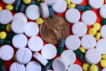 Fototapeta na wymiar One American dollar coin against a background of many white, yellow pills and medicinal capsules without any names or logos