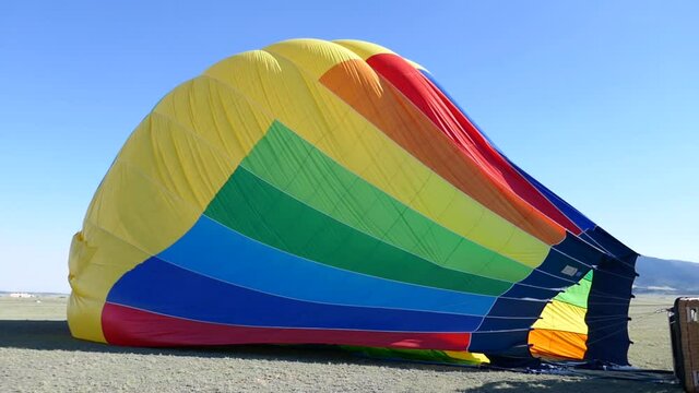 Deflated rainbow colored hot air balloon laying on side