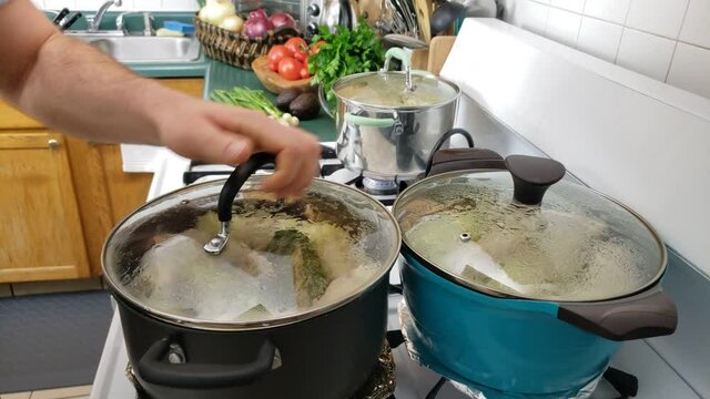 Home cooking - Checking two pots of cabbage rolls being steamed or cooked on gas stove.