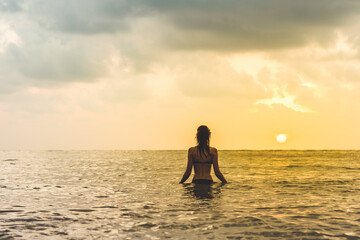 Woman's silhouette against calm sunset beach