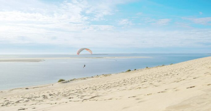 Paraglider Flying Over Grande Dune du Pilat With Scenic View Of Arcachon Bay In France. - wide shot