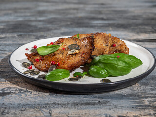 Pork chops with basil on a light plate close-up