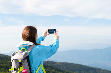 登山後頂上でスマホの撮影をする日本人女性 コピースペースあり